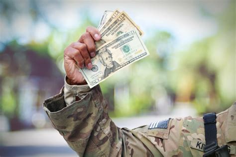 A soldier in uniform, standing in front of a college campus.