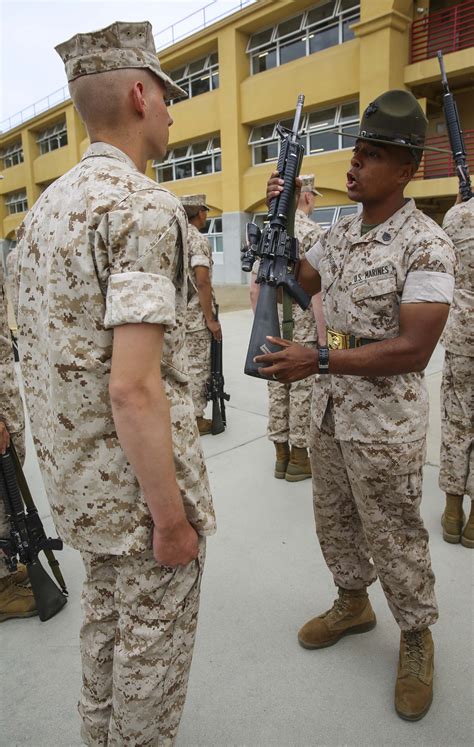 A commander inspecting equipment, with a warehouse or other storage facility in the background