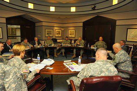 A commander meeting with their personnel, with a map or chart in the background