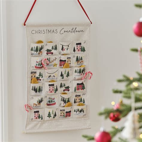 A fabric advent calendar hanging on a wall with 24 pockets