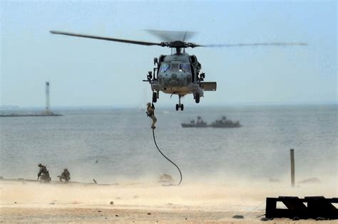 Navy SEALs rappelling from a helicopter